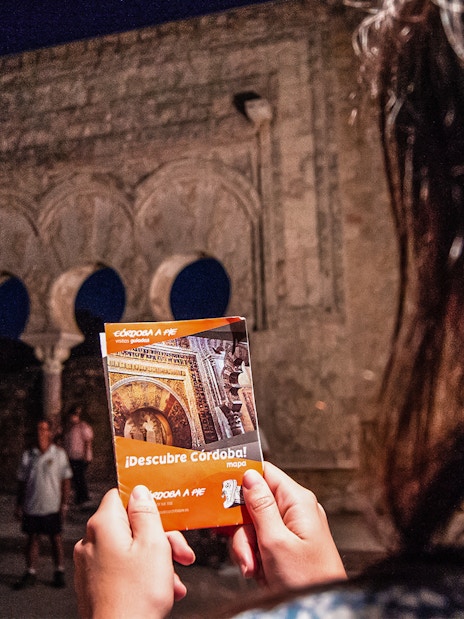 Guided night tour at Medina Azahara with visitors holding a Córdoba map.