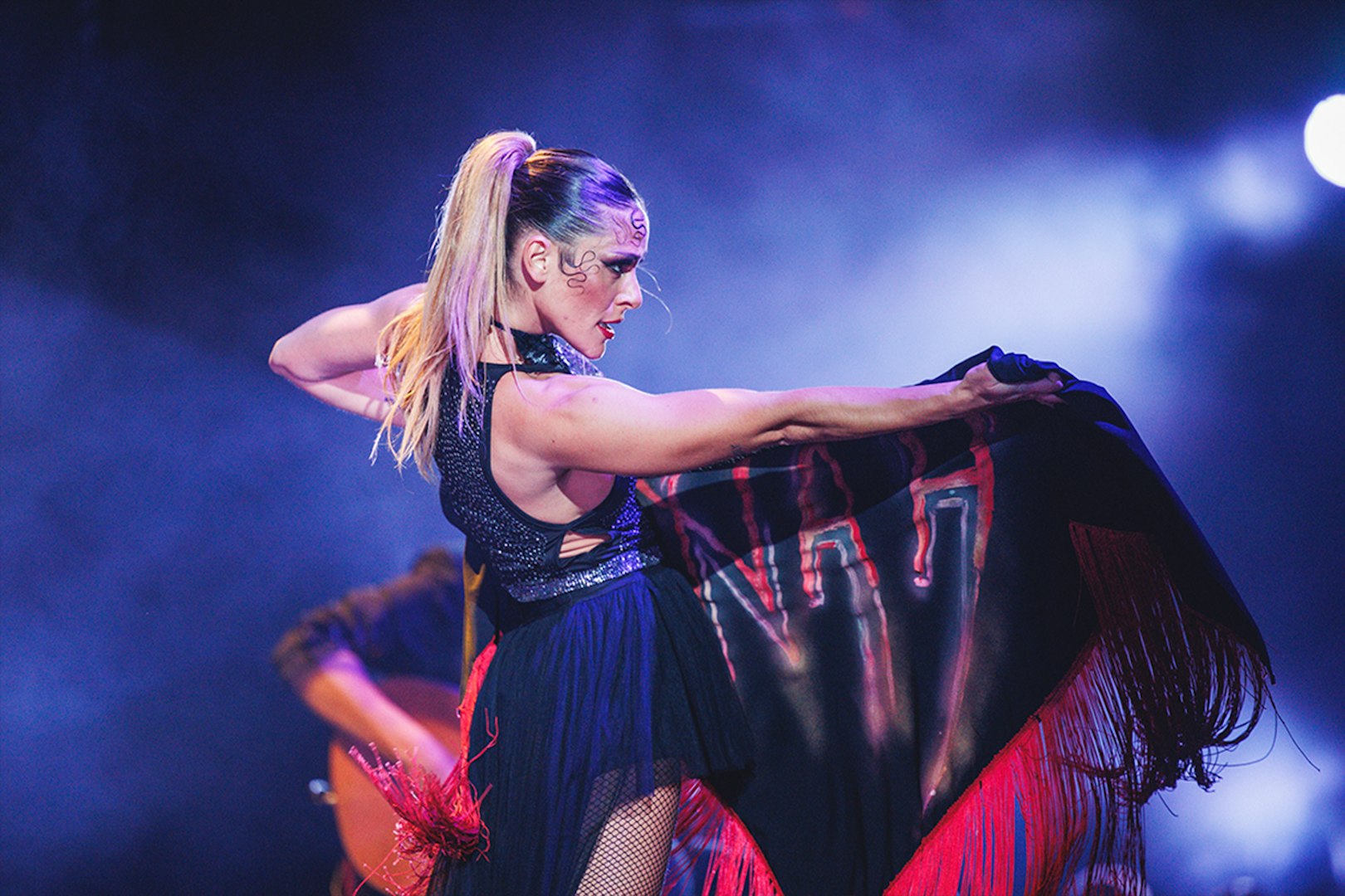 Performer on stage with a black and red shawl during a WAH show.