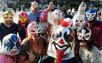 Group wearing colorful Lucha Libre masks at Arena Mexico.