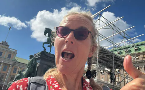 Person in front of Stockholm statue and scaffolding during city exploration game.