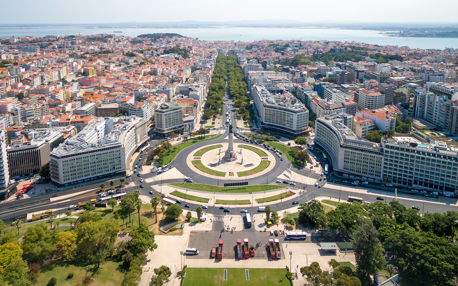 Lisbon Hop on Hop Off bus at Marques de Pombal Square with statue and cityscape in background.