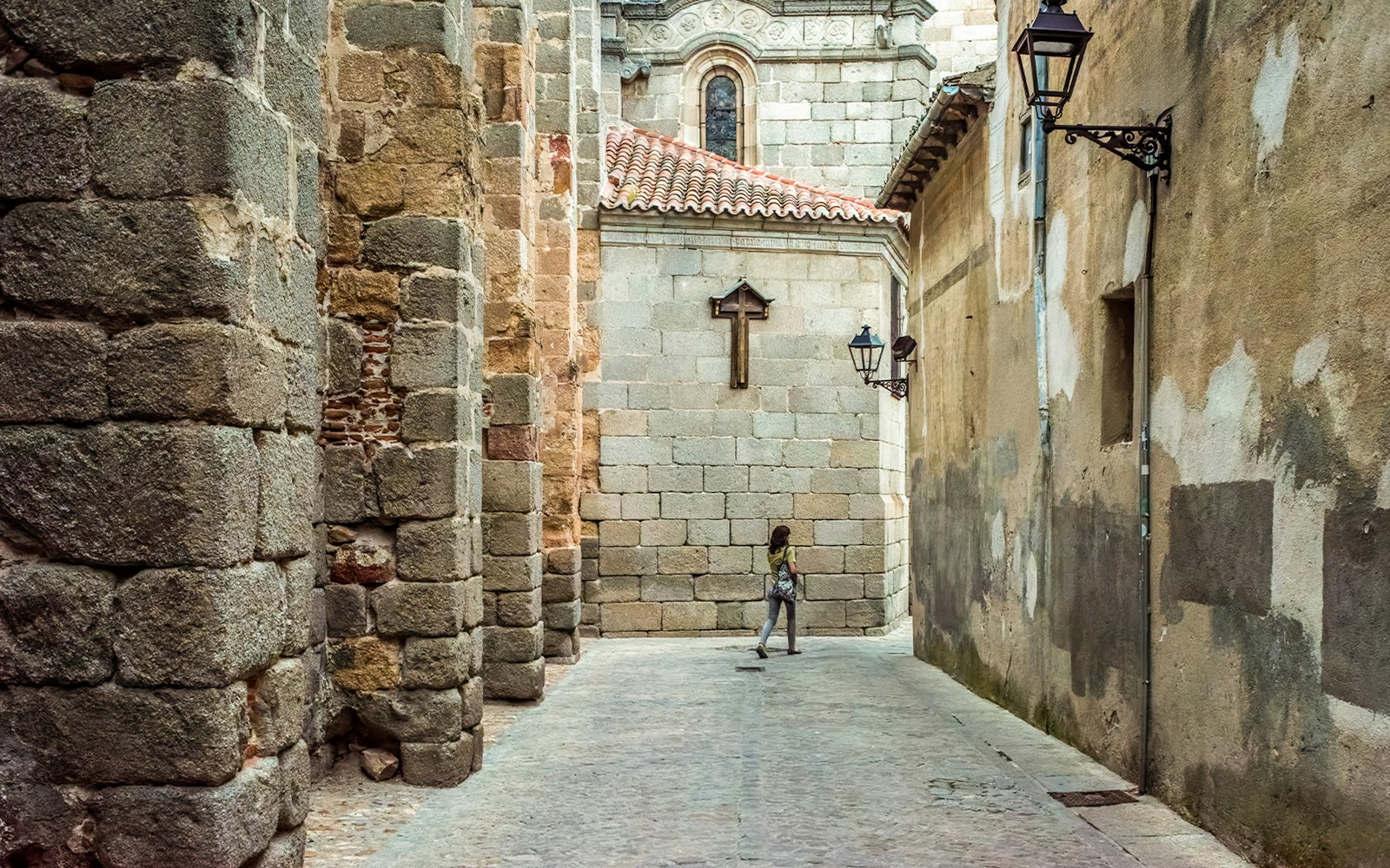Calle Cruz Vieja near Avila Cathedral, stone walls and lanterns, Castilla y Leon, Spain.