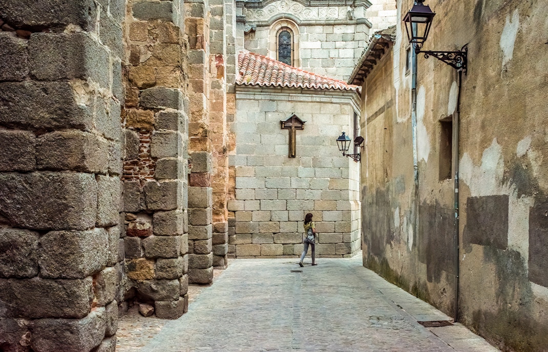 Calle Cruz Vieja near Avila Cathedral, stone walls and lanterns, Castilla y Leon, Spain.
