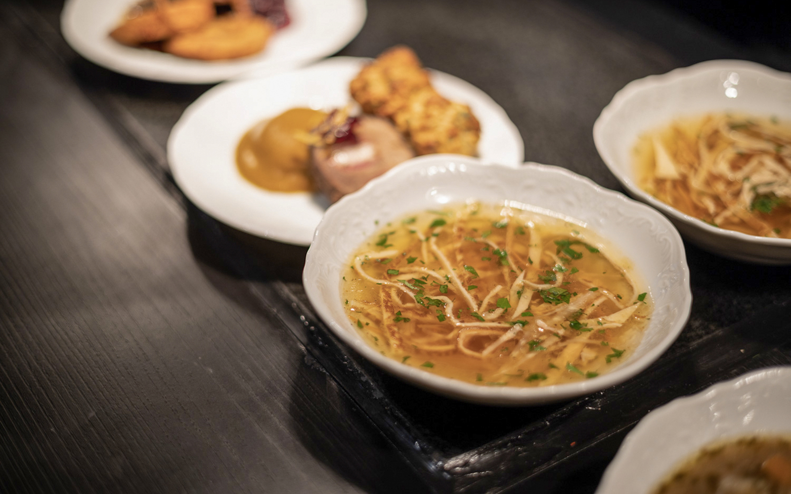 Czech tapas cuisine with noodle soup and traditional dishes on a table.