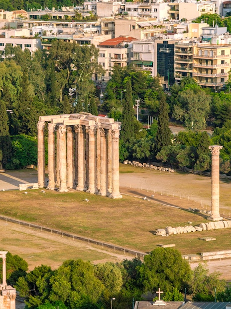Temple of Olympian Zeus ruins in Athens with surrounding cityscape.