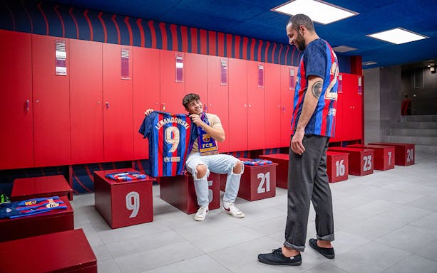 Man holding Lewandowski jersey in FC Barcelona Camp Nou locker room.