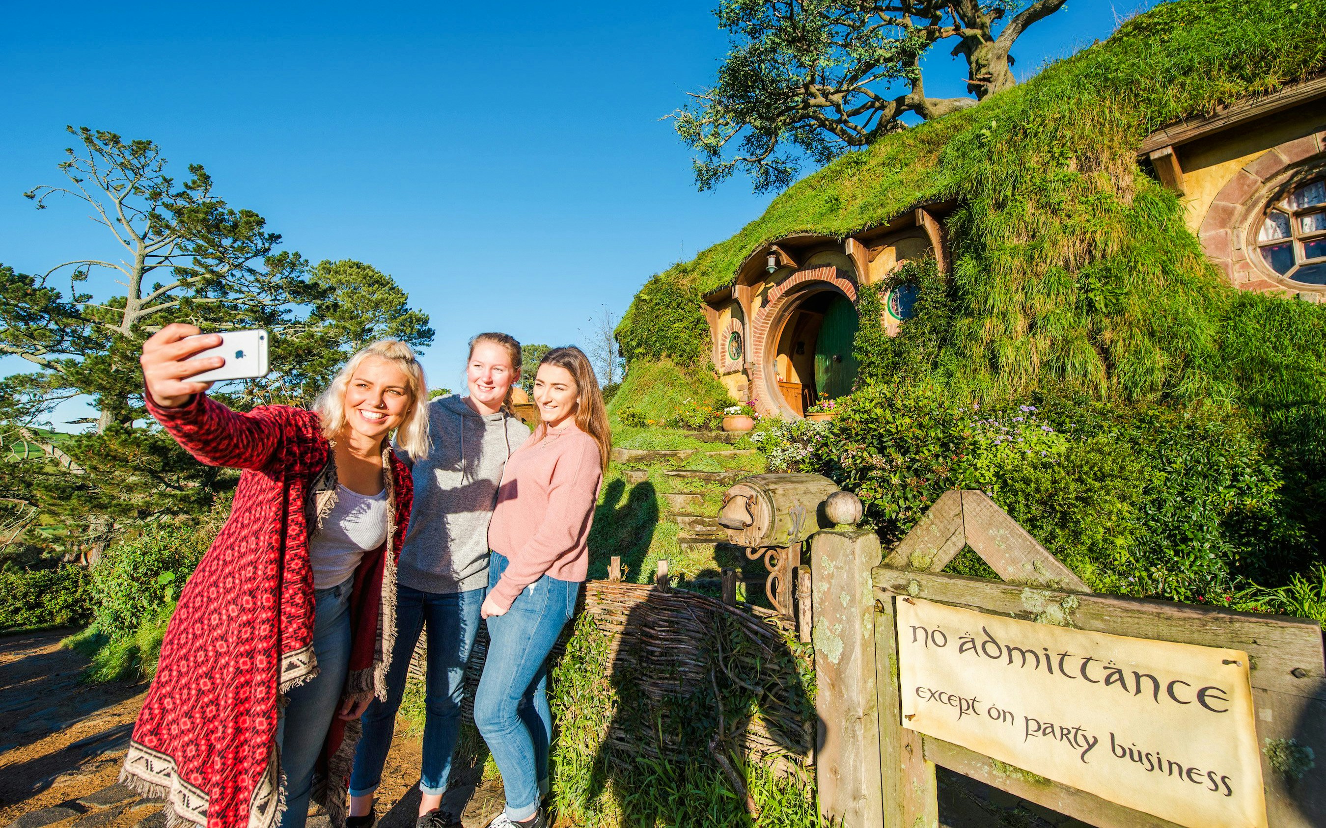 Visitors taking a selfie at Bag End hobbit house, Hobbiton Movie Set, New Zealand.