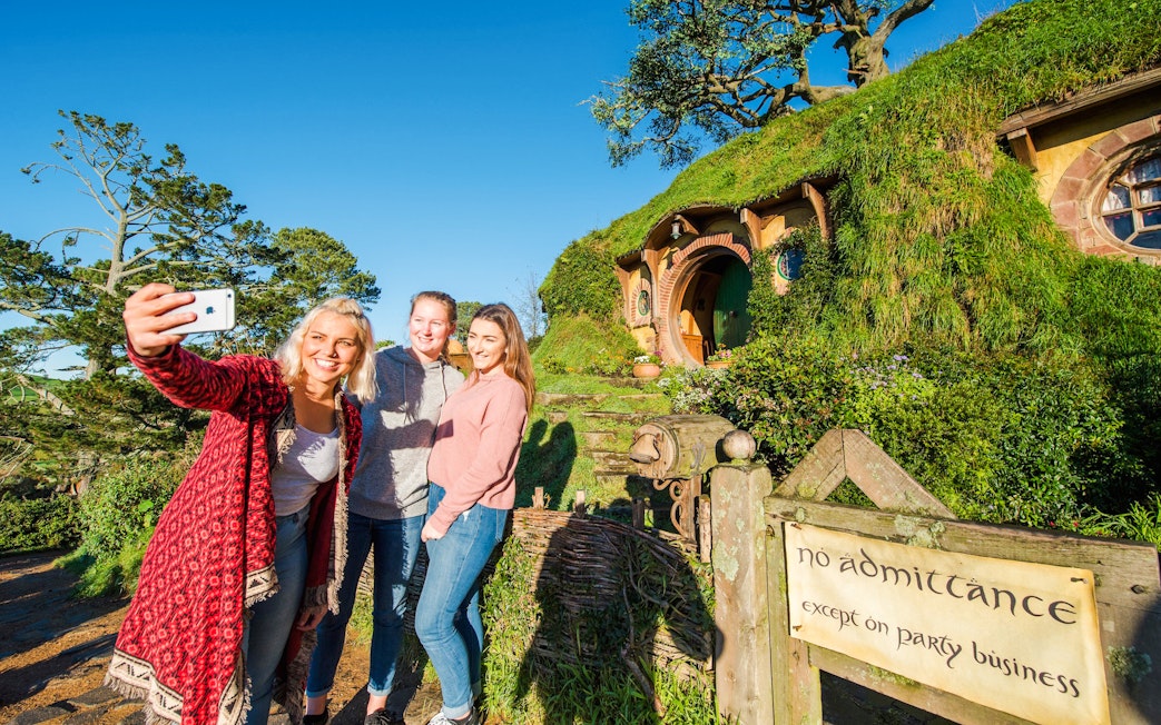 Visitors taking a selfie at Bag End hobbit house, Hobbiton Movie Set, New Zealand.