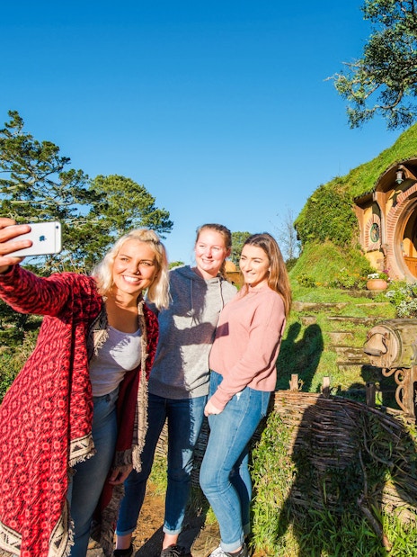 Visitors taking a selfie at Bag End hobbit house, Hobbiton Movie Set, New Zealand.