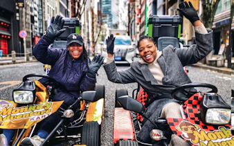 Go-kart riders smiling on Tokyo street during Shibuya to Shinjuku tour.