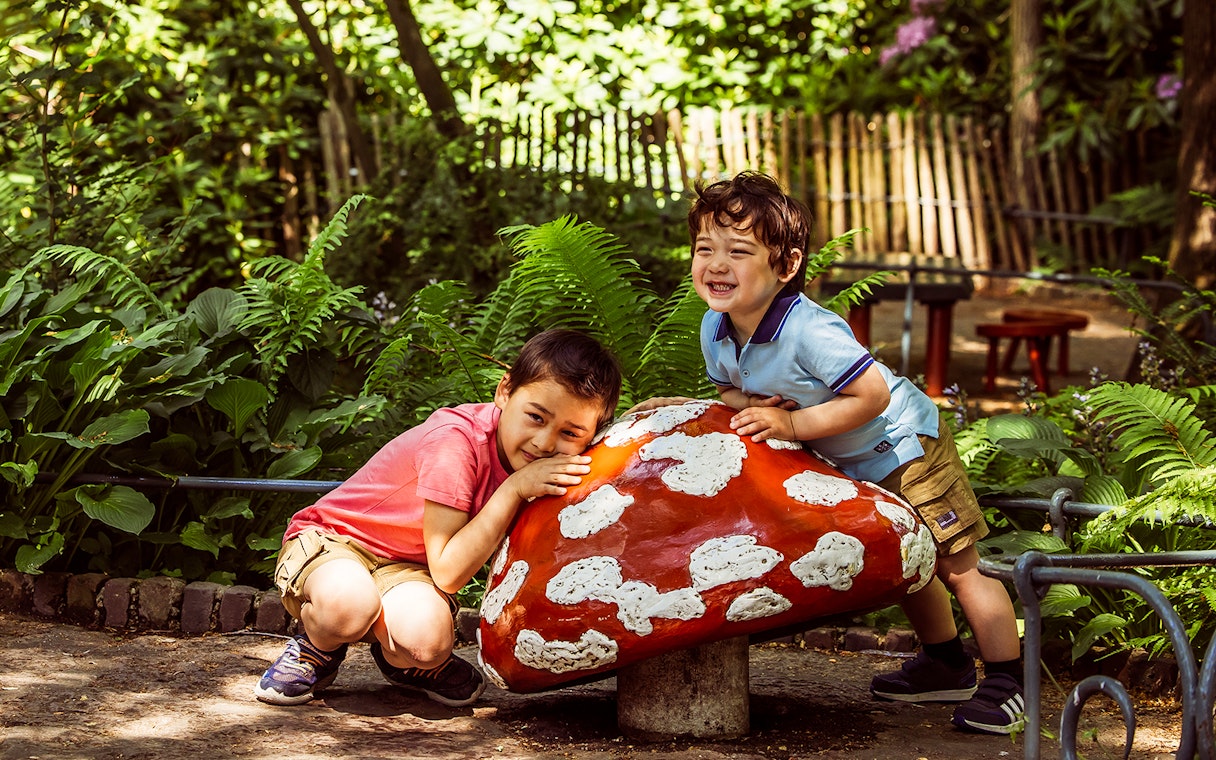 Children playing near a large mushroom sculpture at Efteling theme park.