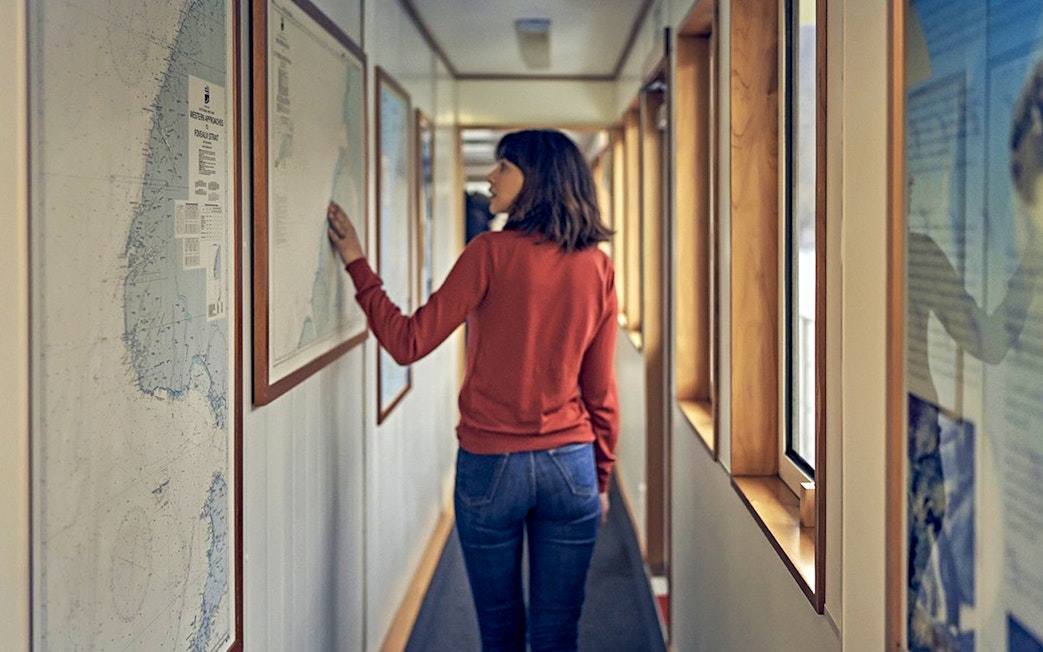 Person examining nautical map on Doubtful Sound cruise ship corridor.