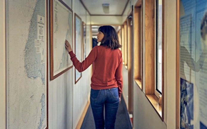 Person examining nautical map on Doubtful Sound cruise ship corridor.
