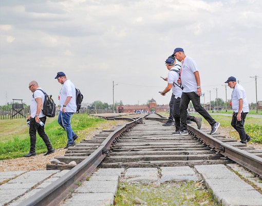 Visitors walking along railway tracks at Auschwitz sub-camps during an exclusive history tour.
