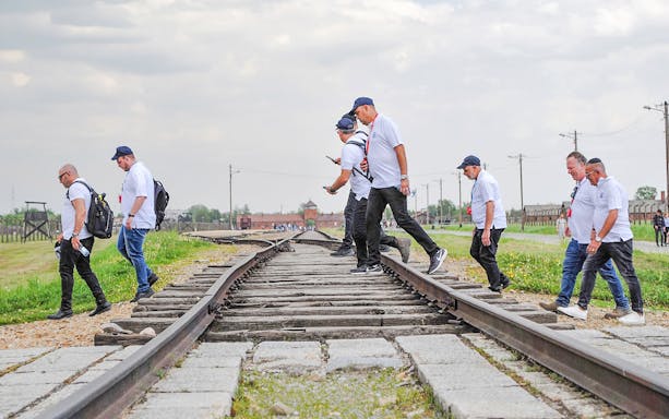 Visitors walking along railway tracks at Auschwitz sub-camps during an exclusive history tour.