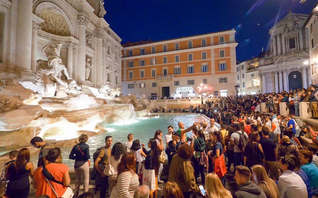 Crowd gathered at Trevi Fountain during Rome night tour.