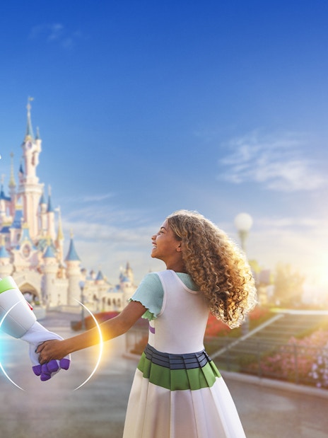 Buzz Lightyear holding hands with a child in front of Sleeping Beauty Castle at Disneyland Paris.