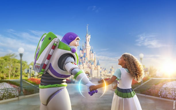 Buzz Lightyear holding hands with a child in front of Sleeping Beauty Castle at Disneyland Paris.