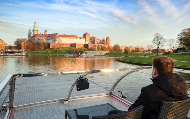 Guest viewing Wawel Castle from a catamaran on Vistula River Cruise, Krakow.