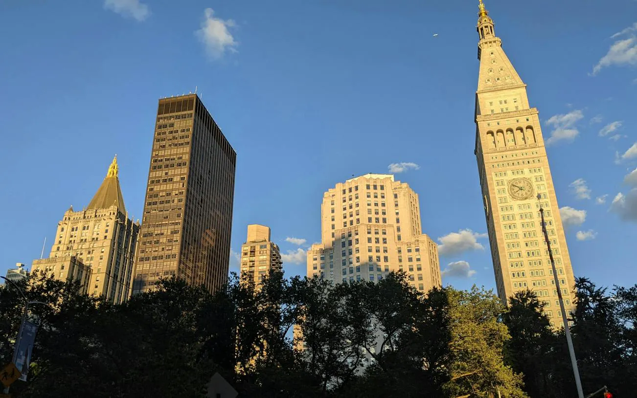 Flatiron Building and surrounding skyscrapers in New York City during sunset.