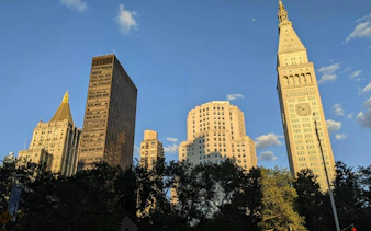 Flatiron Building and surrounding skyscrapers in New York City during sunset.