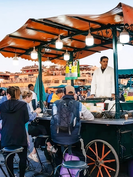 Visitors seated at a food stall in Jemaa el-Fnaa during a Marrakech night walking tour.