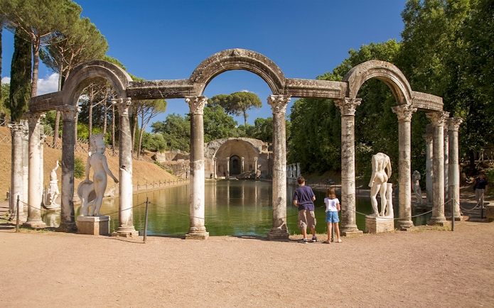 Statues and columns at the Canopus in Hadrian's Villa, Tivoli, with visitors observing.