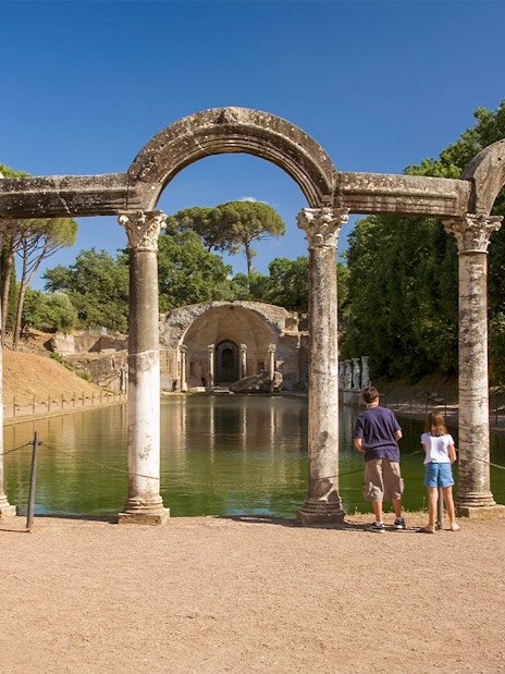 Statues and columns at the Canopus in Hadrian's Villa, Tivoli, with visitors observing.