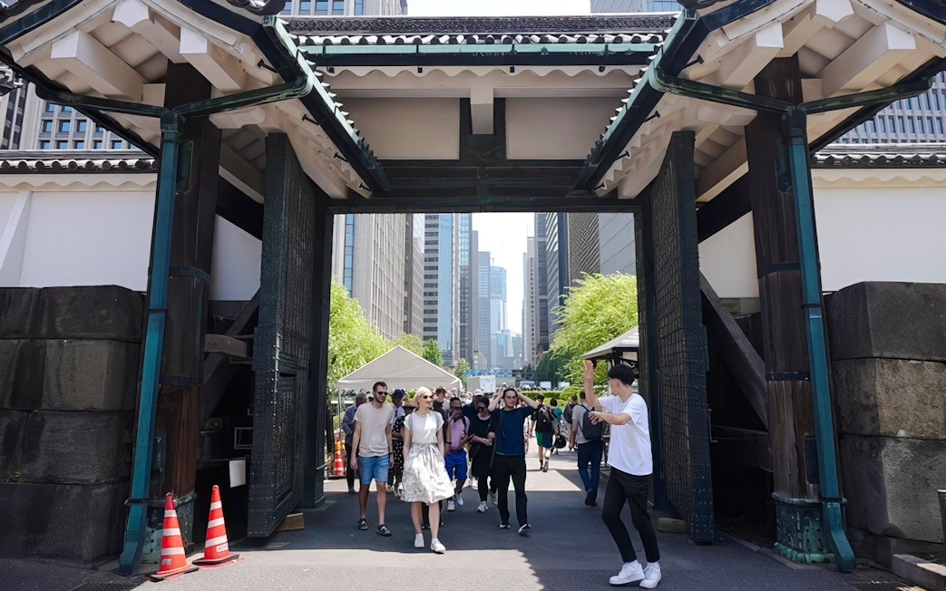 Visitors walking through the gate of Tokyo's Imperial Palace on a guided tour.