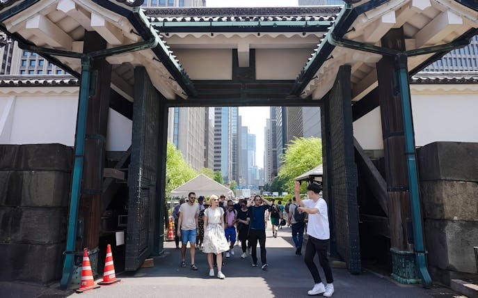 Visitors walking through the gate of Tokyo's Imperial Palace on a guided tour.