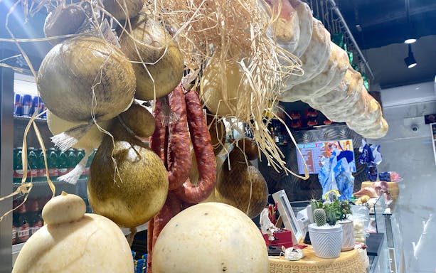 Hanging cured meats and cheeses in a Naples street food market.