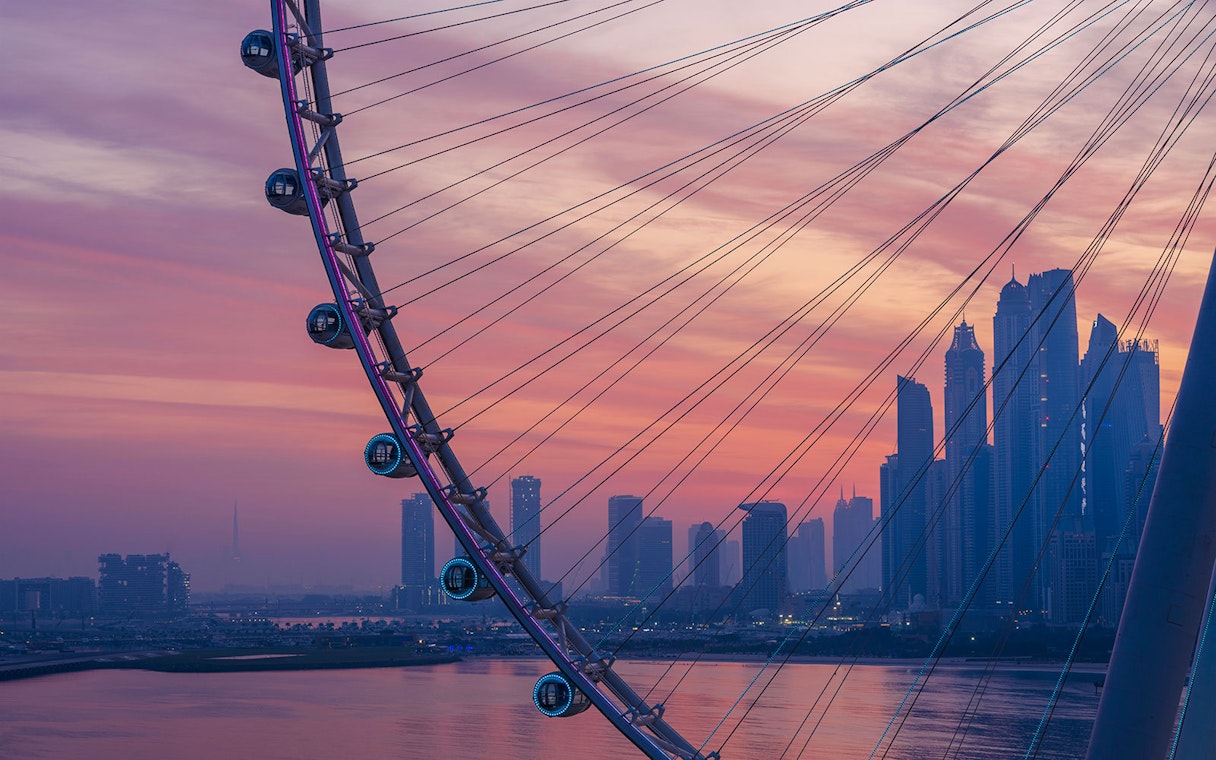 Ain Dubai Ferris wheel with city skyline at sunset.