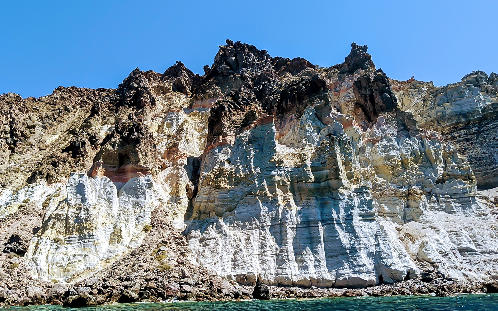 Santorini volcanic cliffs viewed from a private sailing catamaran cruise.