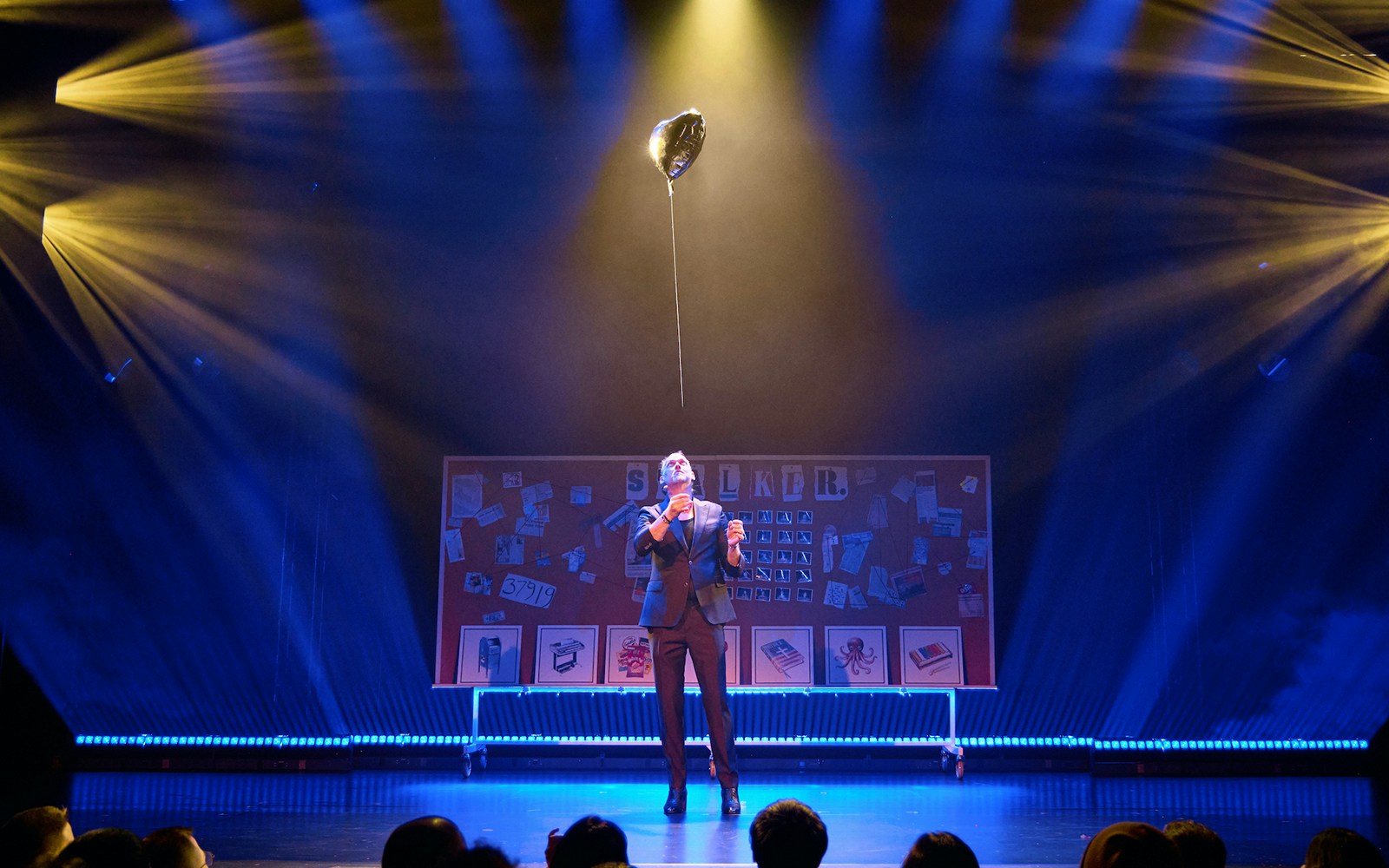 Performer on stage with balloon, board labeled "Stalker" in background.