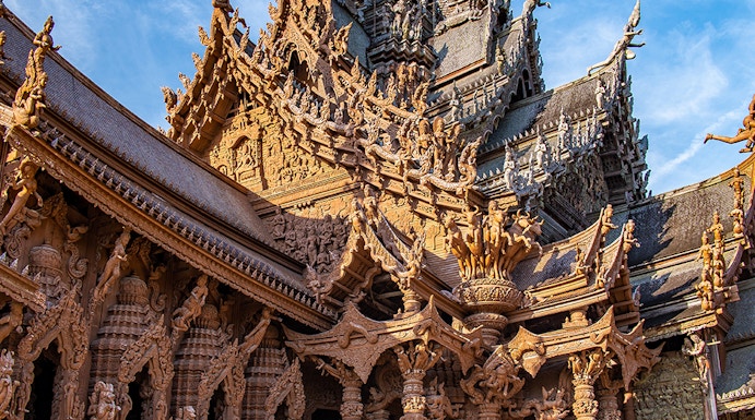 Visitors on horseback in front of the intricate wooden Sanctuary of Truth in Pattaya, Thailand.