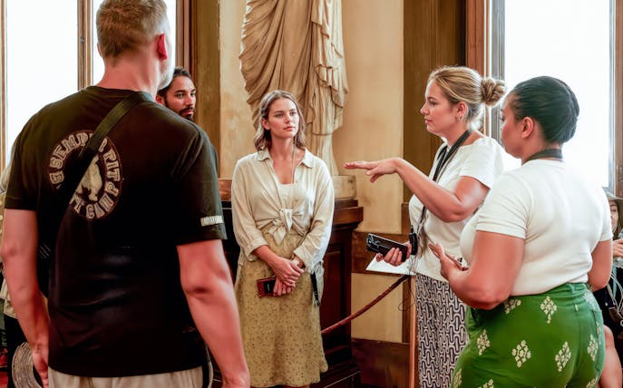 Tour guide explaining artwork to visitors inside Uffizi Gallery, Florence.