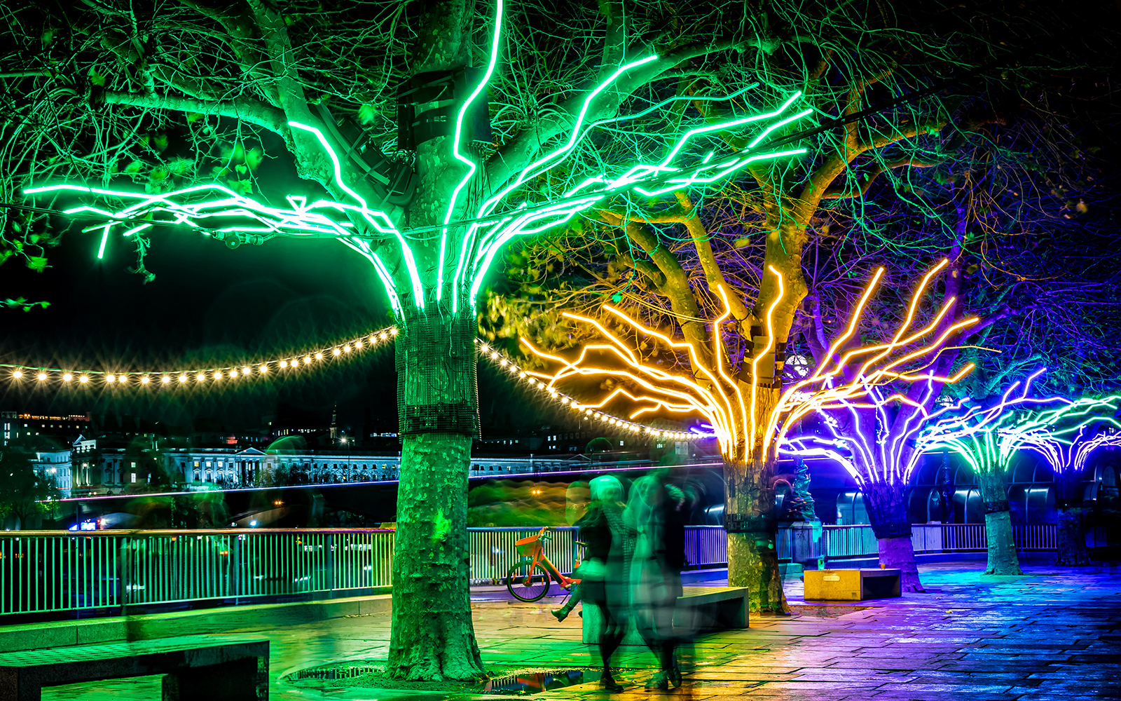 Trees illuminated with colorful neon lights at Southbank Centre's Winter Light Exhibition.
