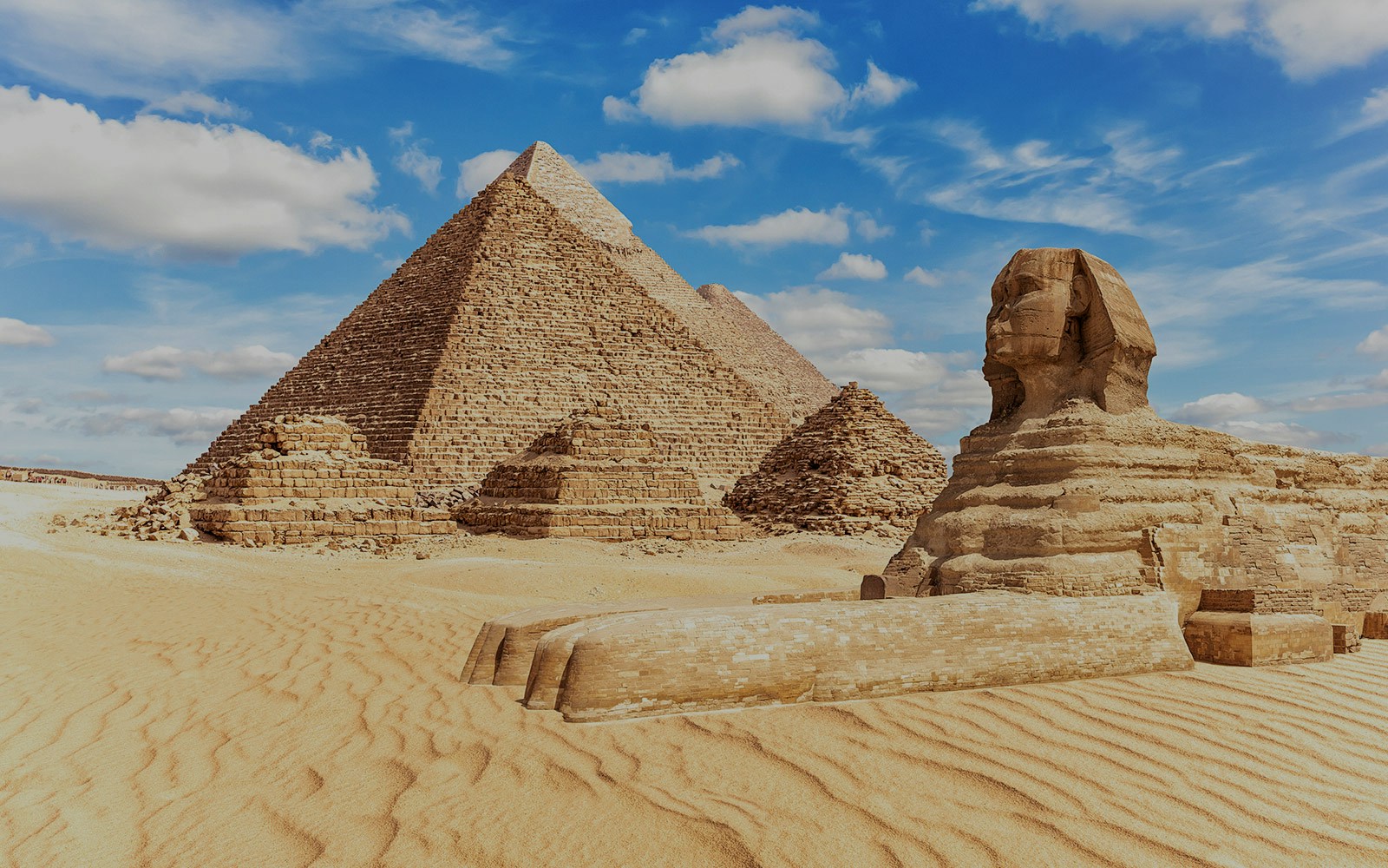 Sphinx and Pyramids of Giza under a blue sky in Egypt.