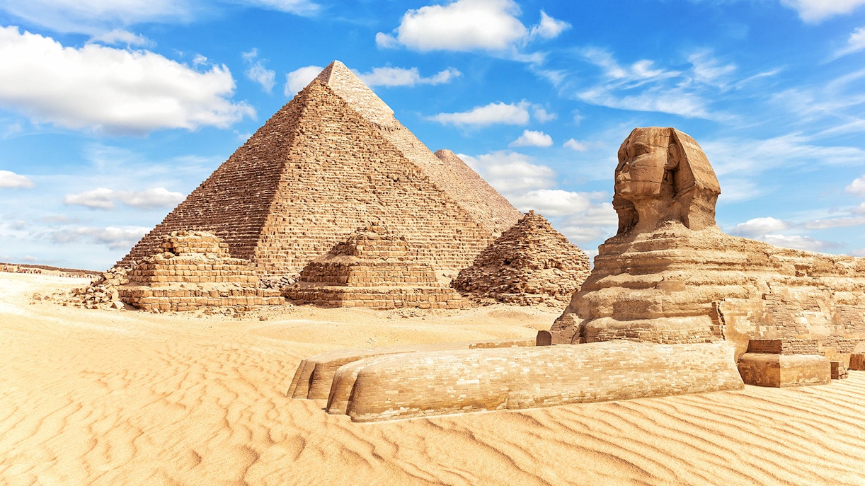 Sphinx and Pyramids of Giza under a blue sky in Egypt.