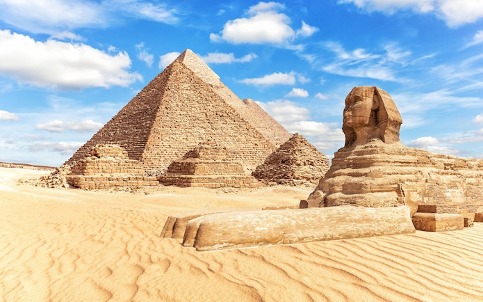 Sphinx and Pyramids of Giza under a blue sky in Egypt.