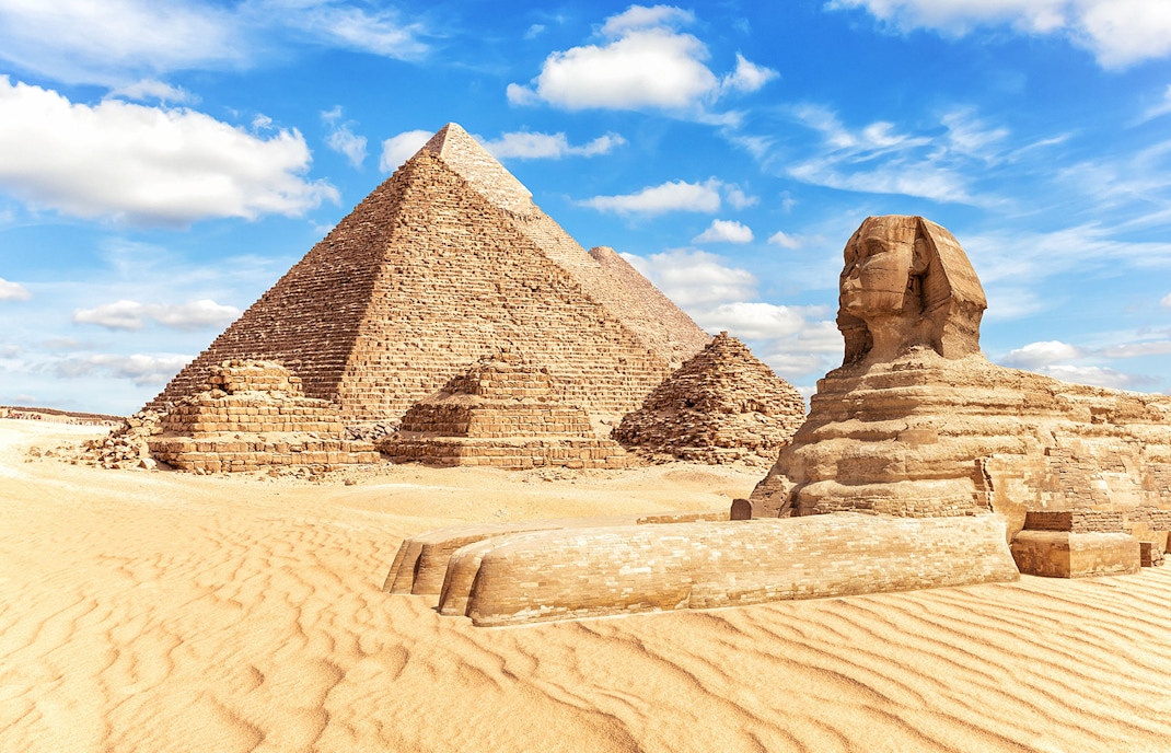 Sphinx and Pyramids of Giza under a blue sky in Egypt.