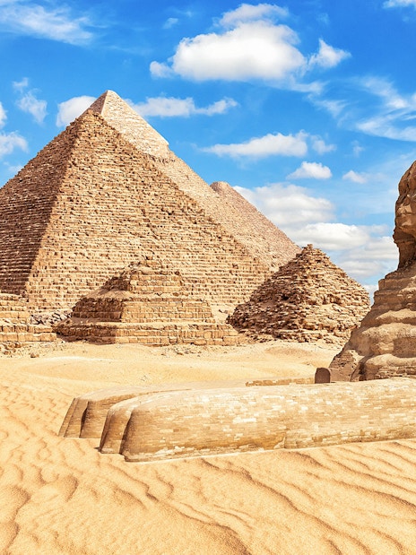 Sphinx and Pyramids of Giza under a blue sky in Egypt.