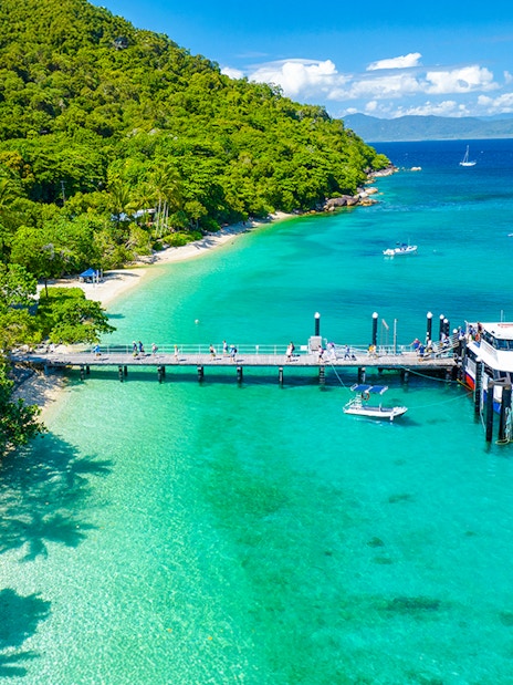 Fitzroy Island pier with tour boat, clear waters, and lush greenery, Cairns day trip.
