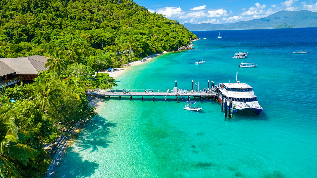 Snorkelers exploring coral reef near Fitzroy Island, glass-bottom boat tour, Cairns day trip experience.