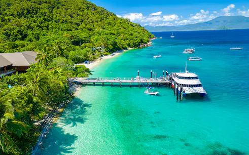 Fitzroy Island pier with tour boat, clear waters, and lush greenery, Cairns day trip.