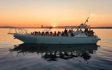 Tourists enjoying a sunset cruise on a boat with a view of the horizon.