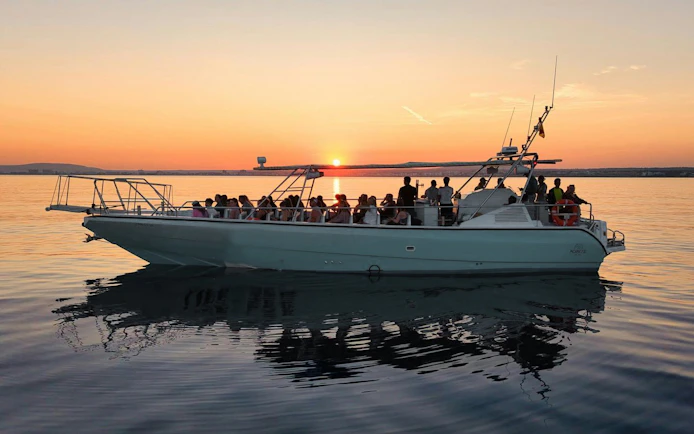 Tourists enjoying a sunset cruise on a boat with a view of the horizon.