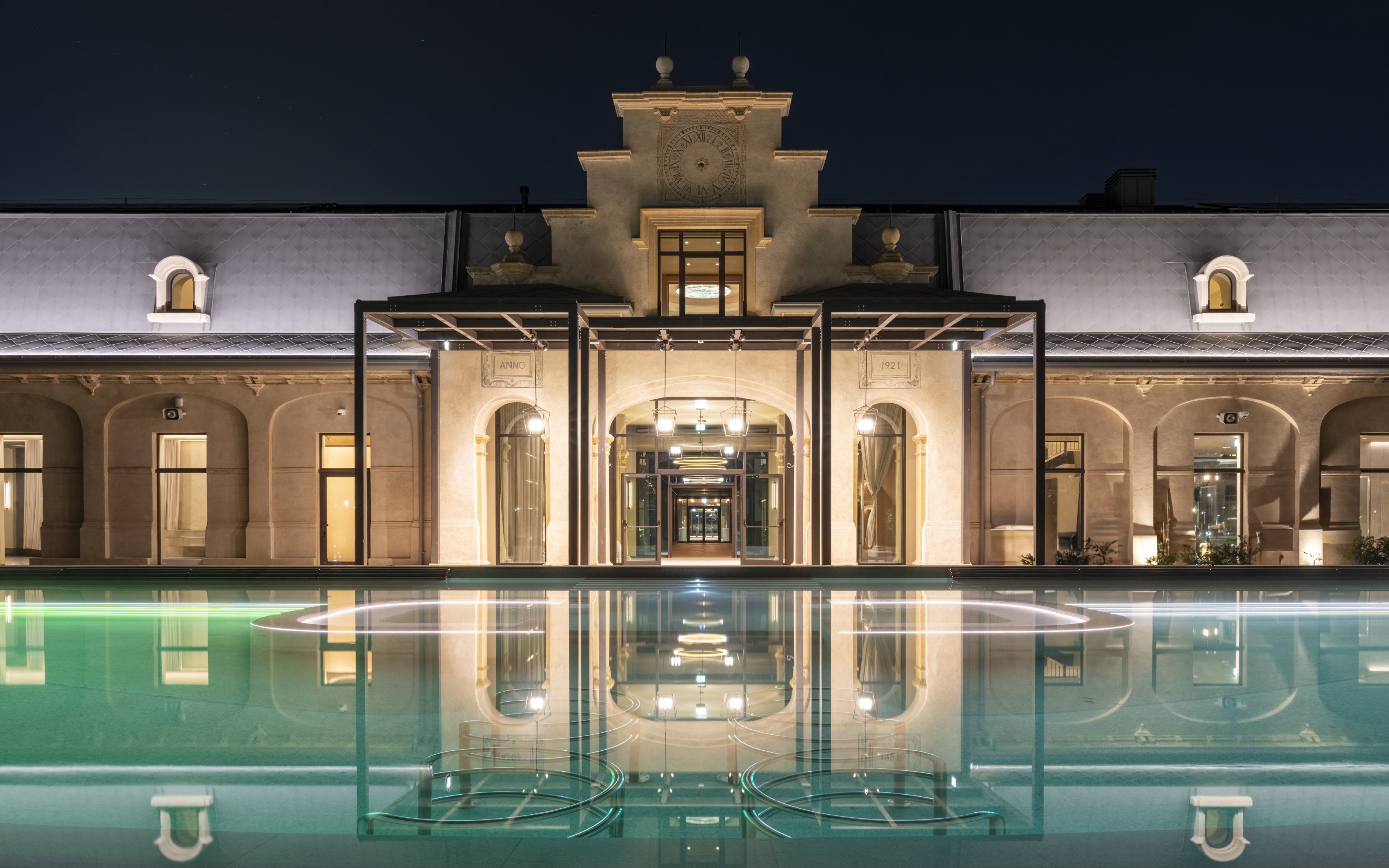 Milan spa exterior with illuminated pool at night.