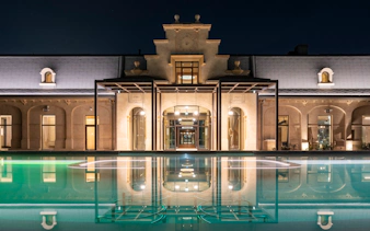 Milan spa exterior with illuminated pool at night.