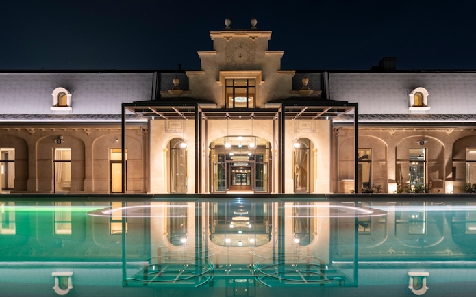 Milan spa exterior with illuminated pool at night.